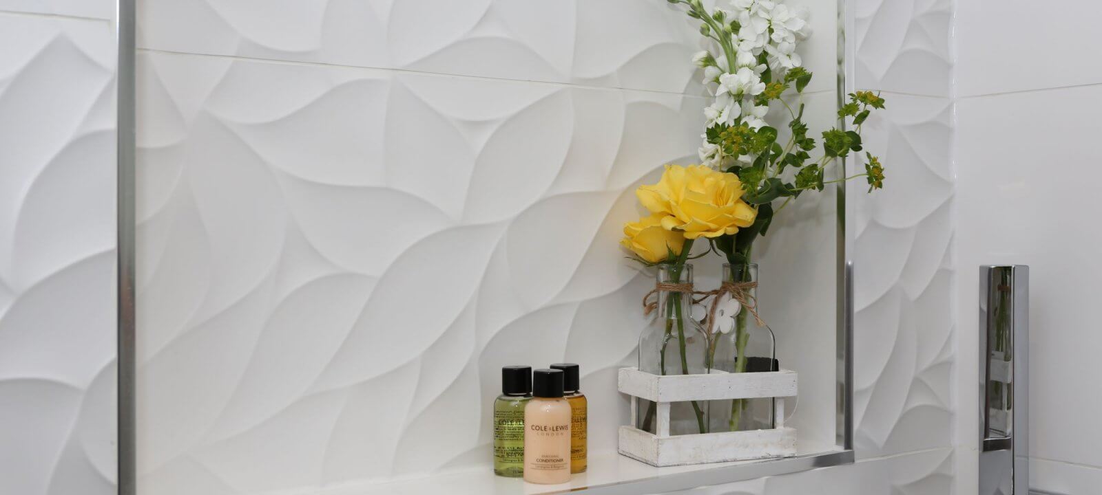 inset in bathroom wall with flower arrangement and toiletries