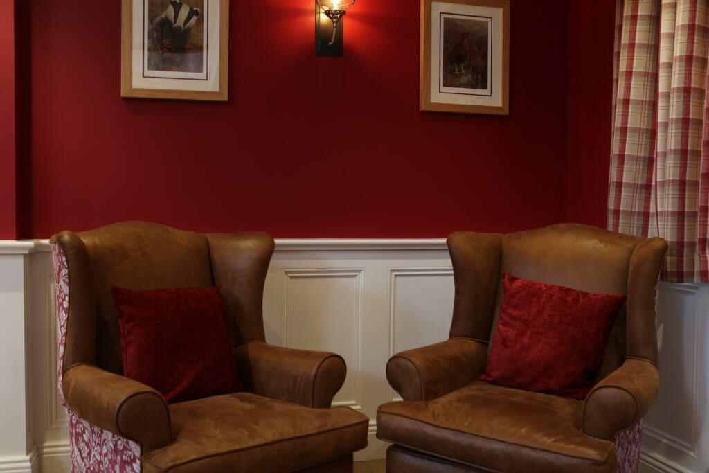 Two brown leather armchairs with red cushions
