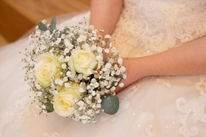 Close up of bouquets of flowers being held by a woman in bridal dress