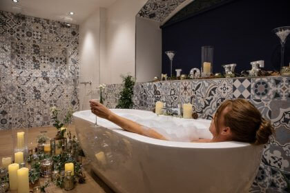 woman relaxing in bubble bath holding champagne glass