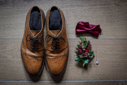 brown shows, bow tie and buttonhole flower on wooden floor