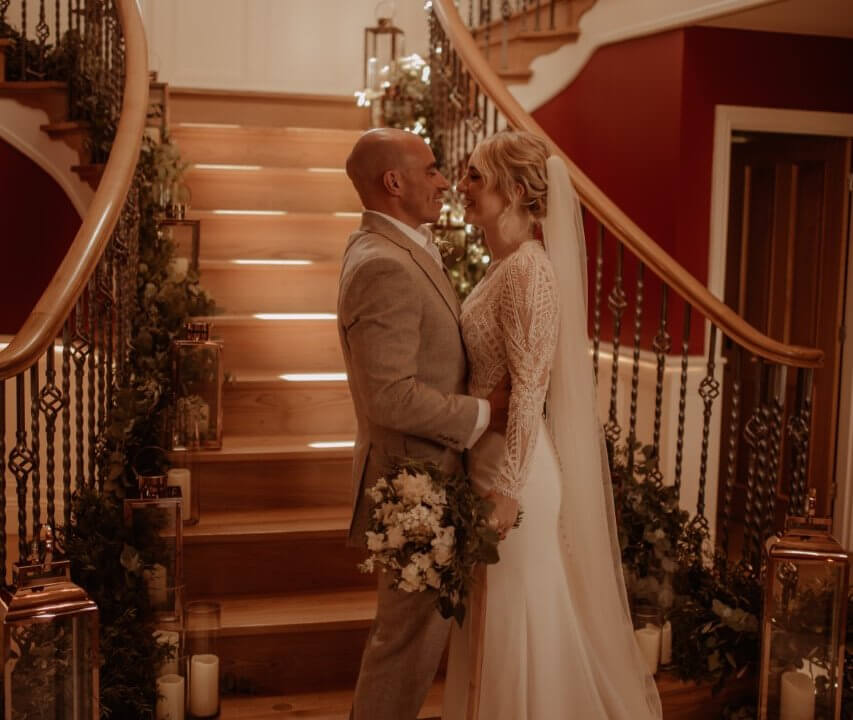 bride and groom standing in front of staircase inside Spicer Manor